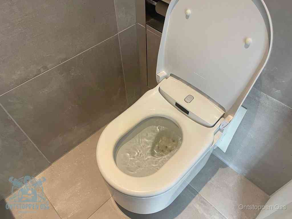 Een toiletpot vol troebel water met drijvend papier en restanten, de meest voorkomende oorzaak van een verstopte wc in Oss