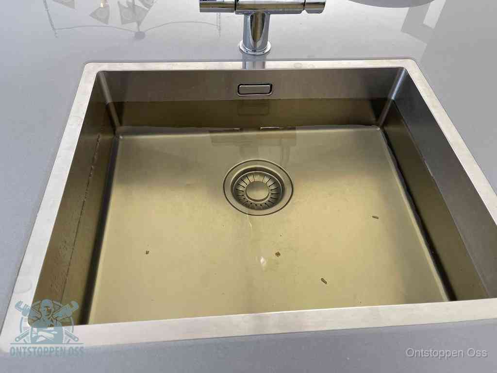 Stilstaand water in een rvs spoelbak dat niet wegloopt, een duidelijk signaal van een gootsteenverstopping in Oss