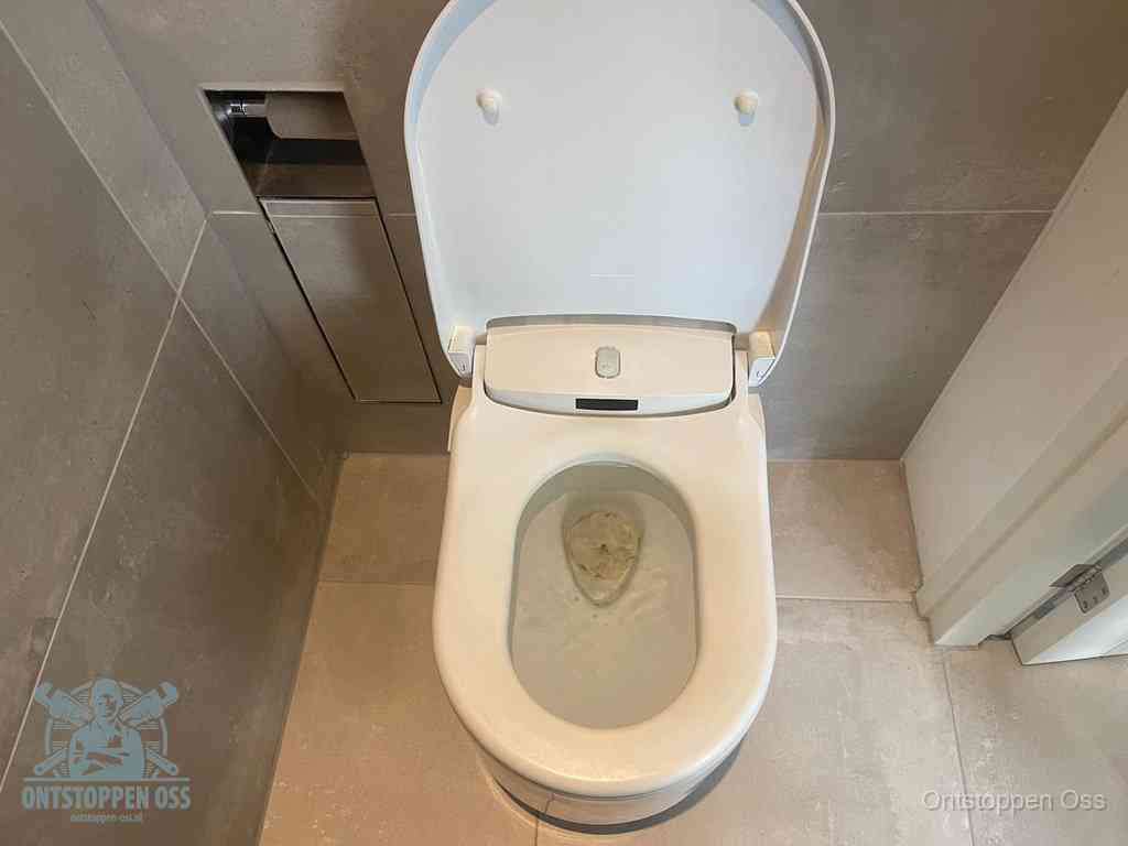 Een wit hangtoilet waarin een prop wc-papier op het water blijft drijven, een duidelijk signaal van een verstopte wc in Oss