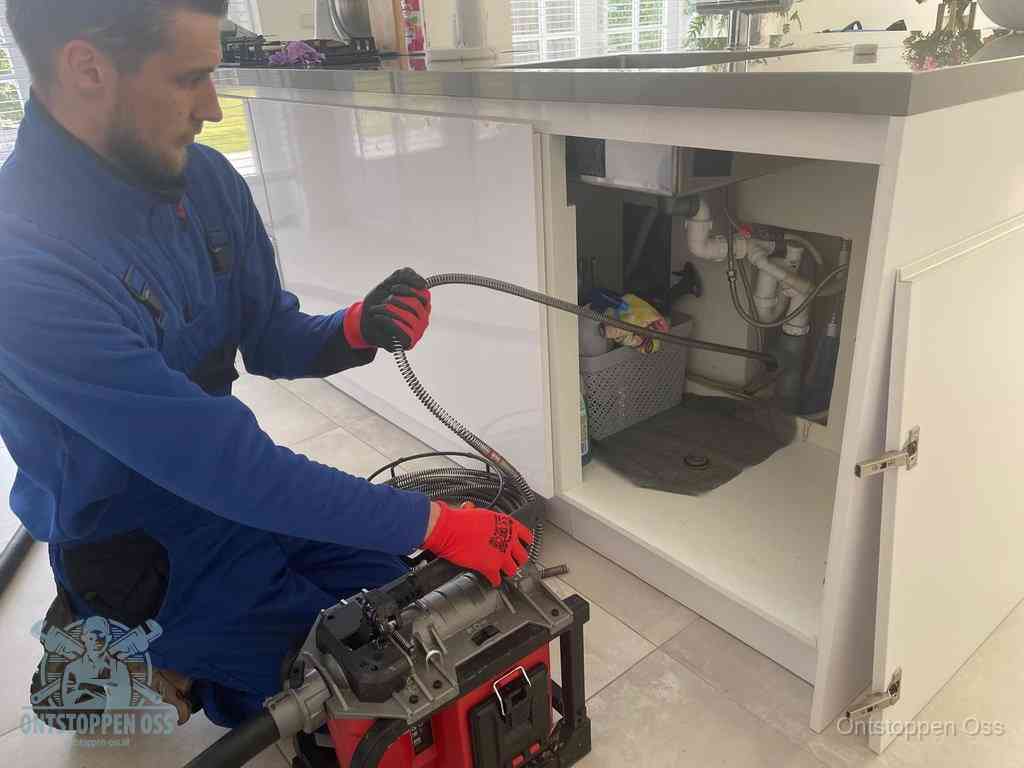Een monteur reinigt de keukenafvoer grondig met een veermachine om terugkerende gootsteenverstoppingen te voorkomen in Oss