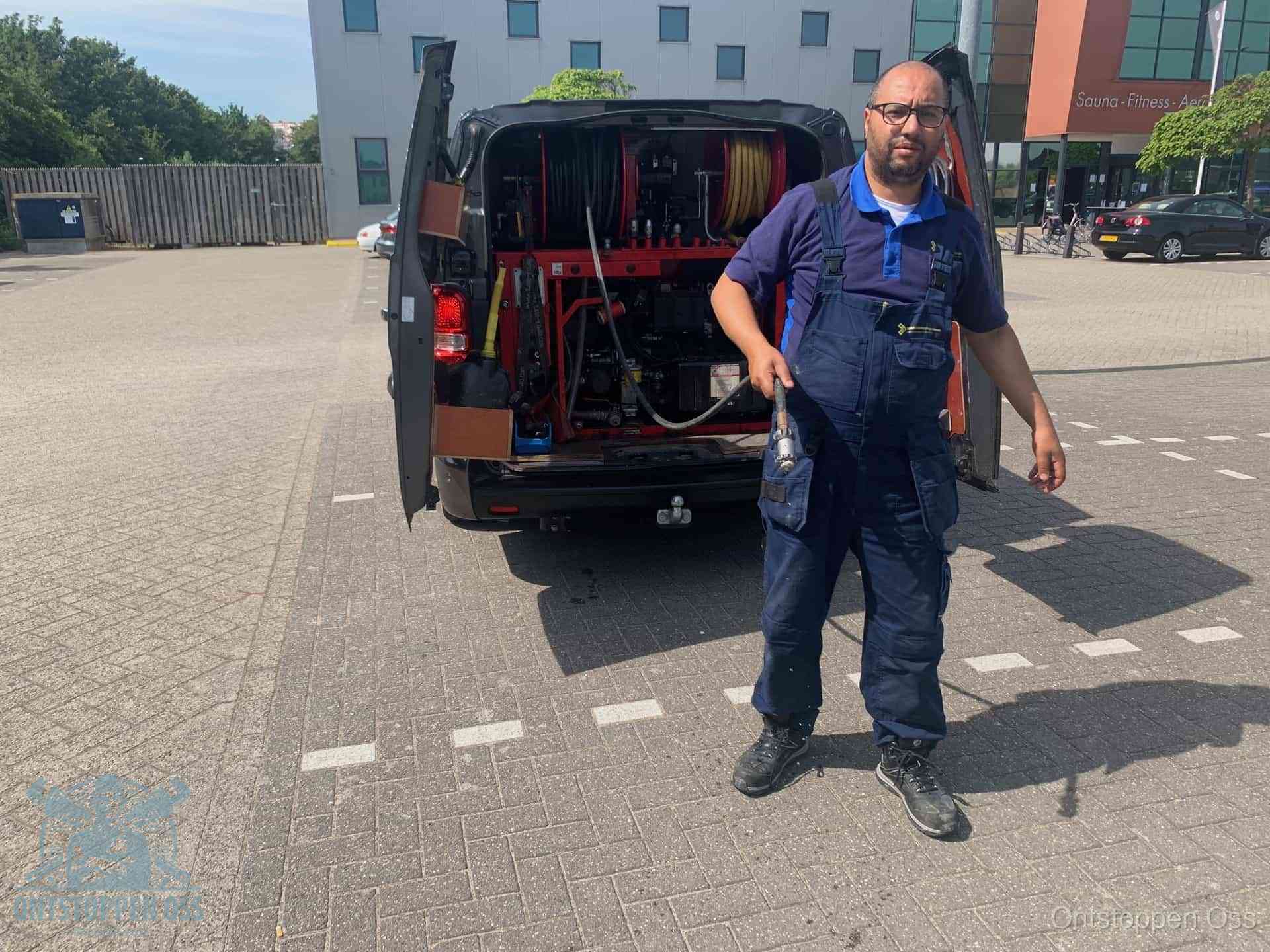 Een monteur bij zijn bestelbus met een hogedruk- en rioolreinigingsunit, klaar om de oorzaak van terugkerende wc-verstoppingen aan te pakken in Oss