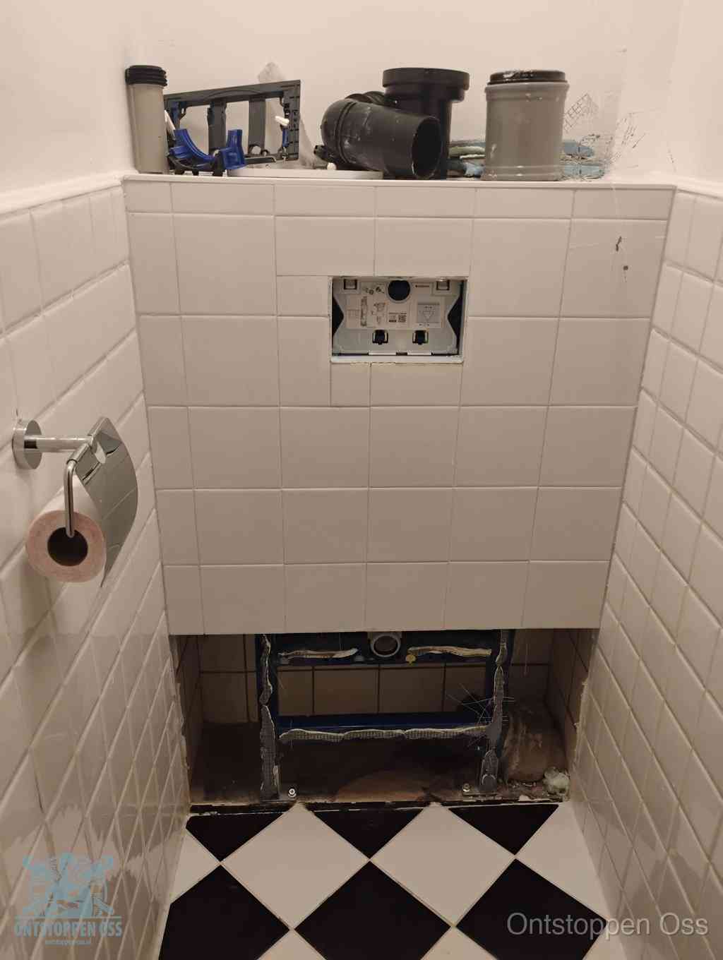 Een toiletruimte waar het hangtoilet en de inbouwreservoir-onderdelen zijn vrijgelegd voor onderhoud, periodiek nazicht voorkomt een wc-verstopping in Oss